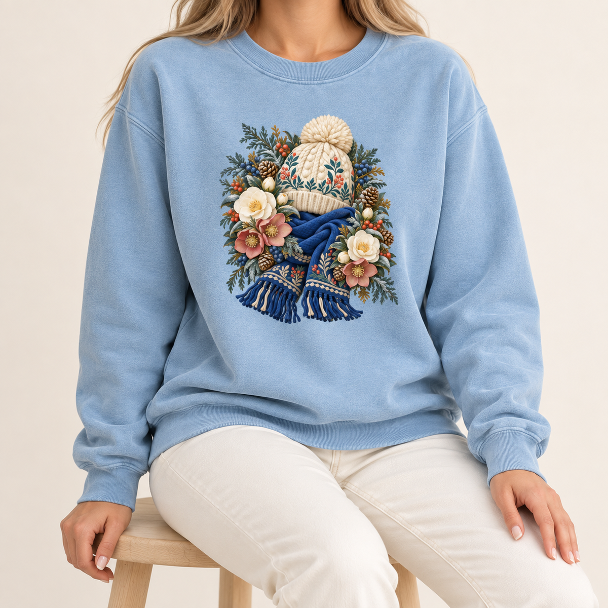 Floral knit hat and scarf design printed direct-to-garment on garment-dyed fleece — a cream pom-pom hat above a deep blue fringed scarf, framed by evergreen, pinecones and cream roses