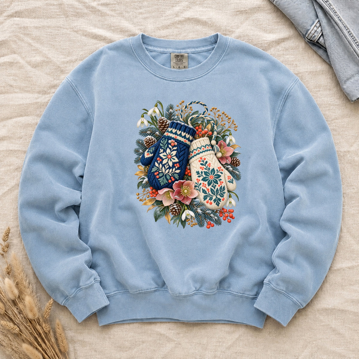 Floral Winter Mittens Sweatshirt in Chambray — pale winter-sky blue, with a deep navy and a cream mitten in a winter bouquet of evergreen, pinecones and berries