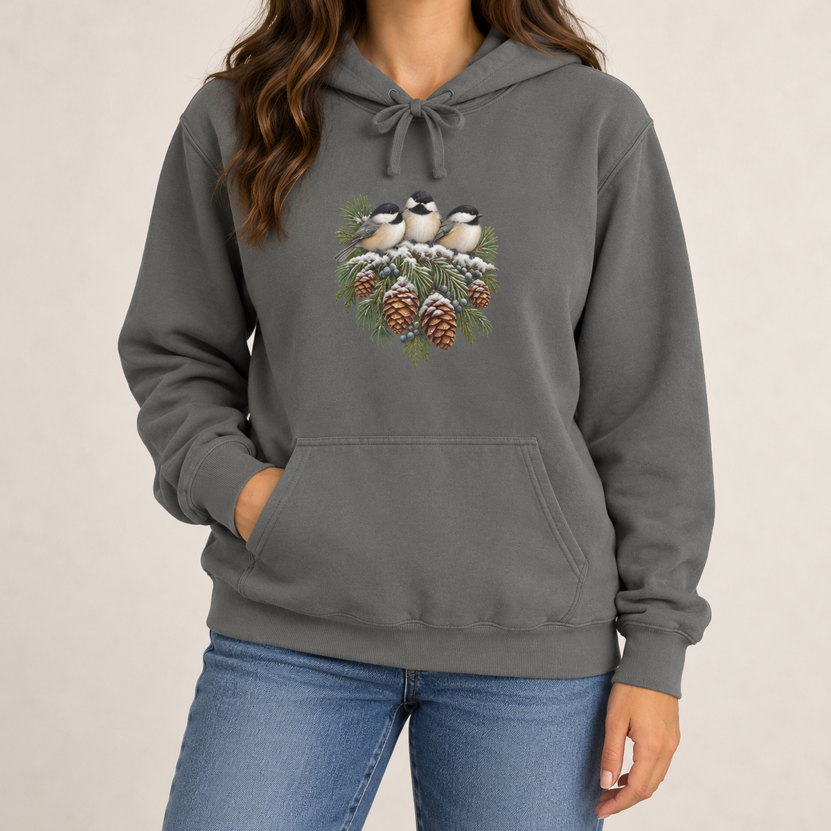 Winter Chickadee hoodie in Grey worn, front view with three chickadees on a snowy spruce bough