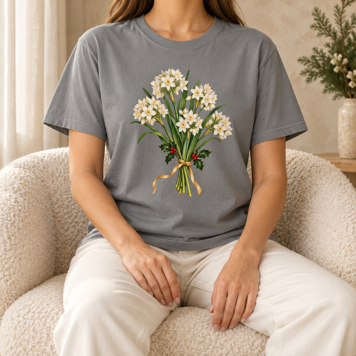 December birth flower t-shirt in Grey worn by a woman – a watercolor bouquet of paperwhite narcissus and holly tied with a gold ribbon, printed on a garment-dyed Comfort Colors cotton tee