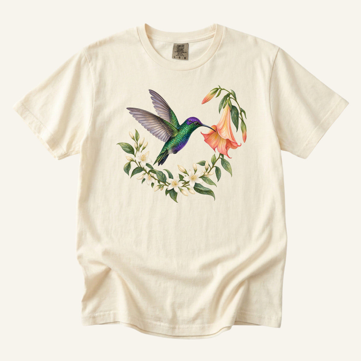 Hummingbird T-Shirt in Ivory — an emerald hummingbird at a peach angel's trumpet with white jasmine, on garment-dyed cotton