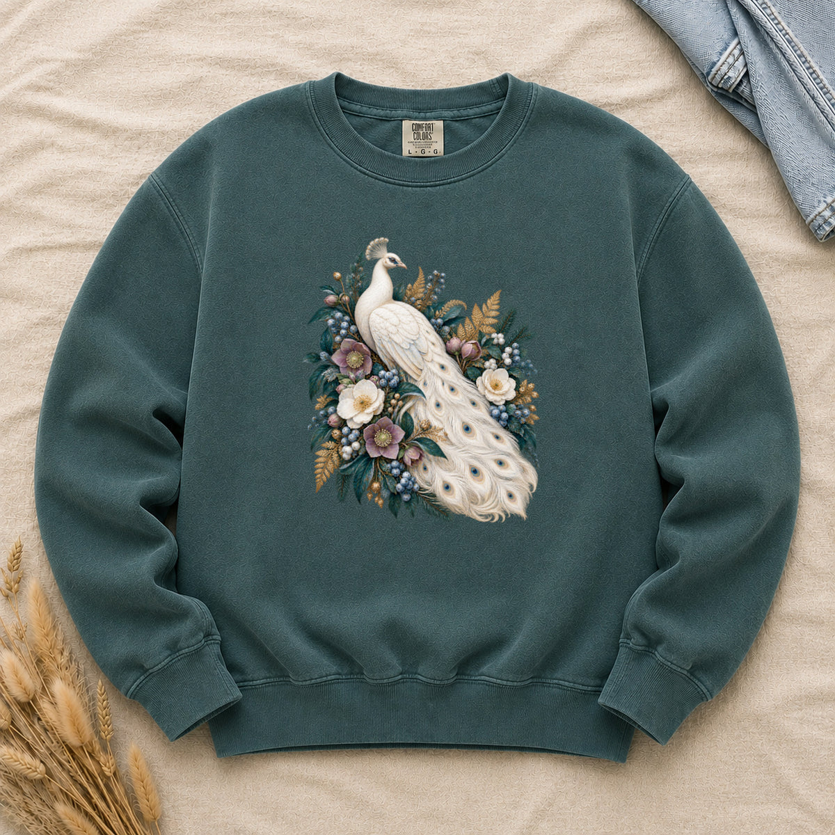 Ivory Peacock and Floral Sweatshirt in Blue Spruce — an ivory peacock among cream and dusty purple flowers, blue berries and deep green leaves, its long tail curving down through the arrangement with small blue and gold markings on the pale feathers