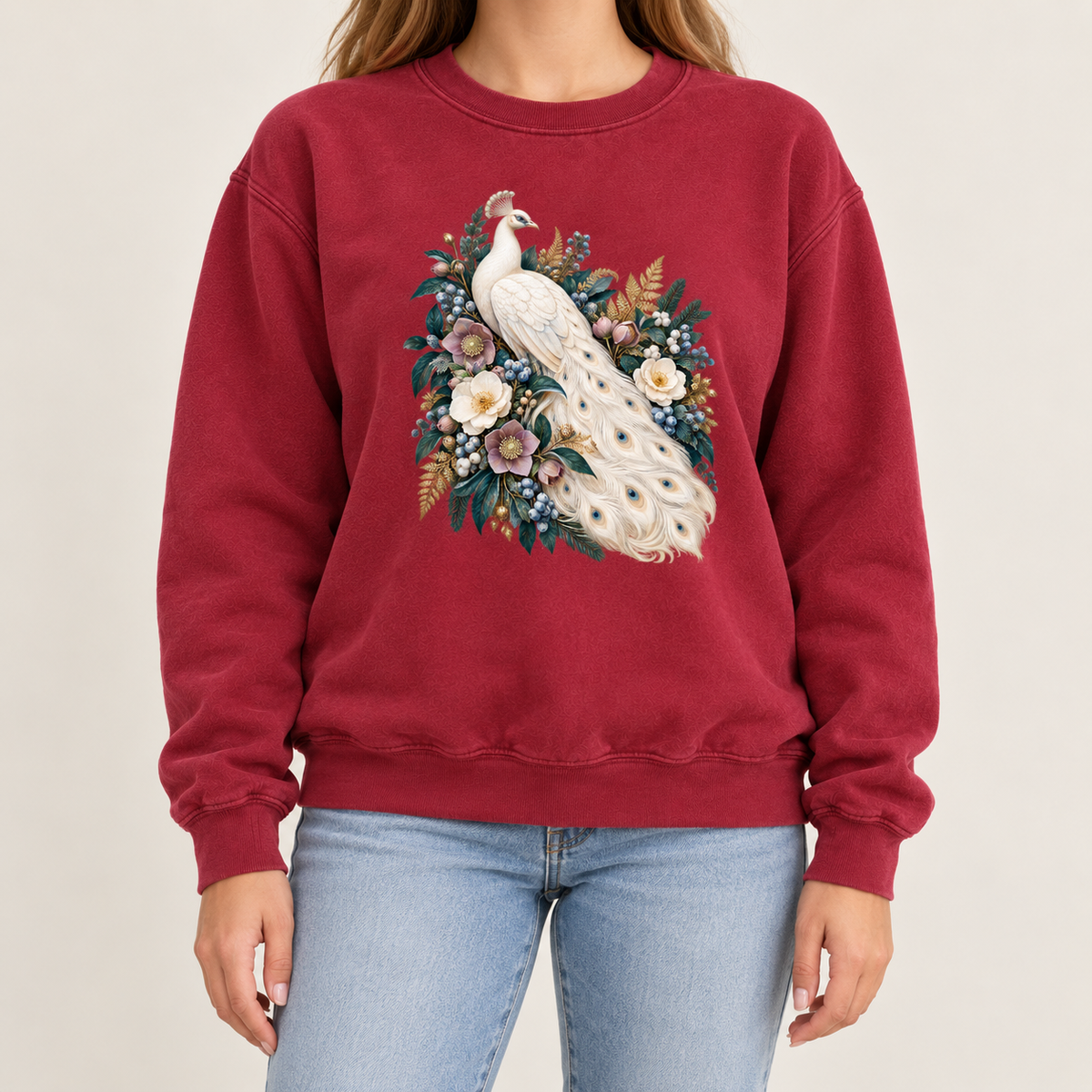 Antique-style peacock illustration printed on a 9.5 oz garment-dyed cotton-blend crewneck pullover — an ivory peacock with a long curving tail among cream and purple flowers and deep green leaves