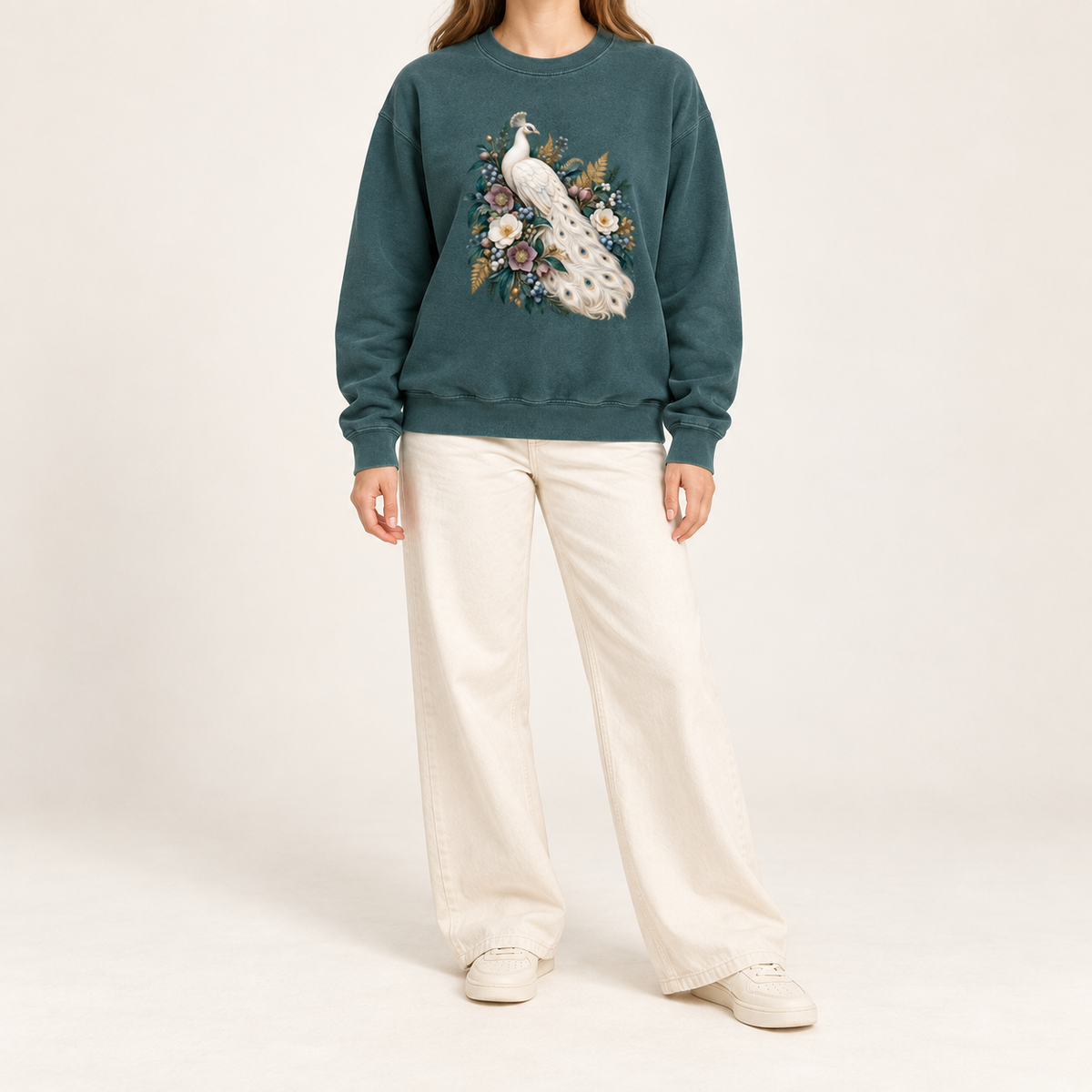 Pale peacock plumage printed on a dark garment-dyed ground with no panel behind the artwork — an ivory peacock with a long curving tail among cream and purple flowers and deep green leaves
