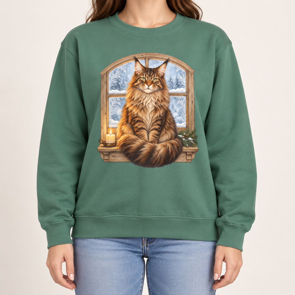 Maine Coon at the window sweatshirt in Light Green – a tabby Maine Coon on a frosted windowsill with a candle and pine, snowy forest through an arched window, printed large on the chest of a Comfort Colors crewneck