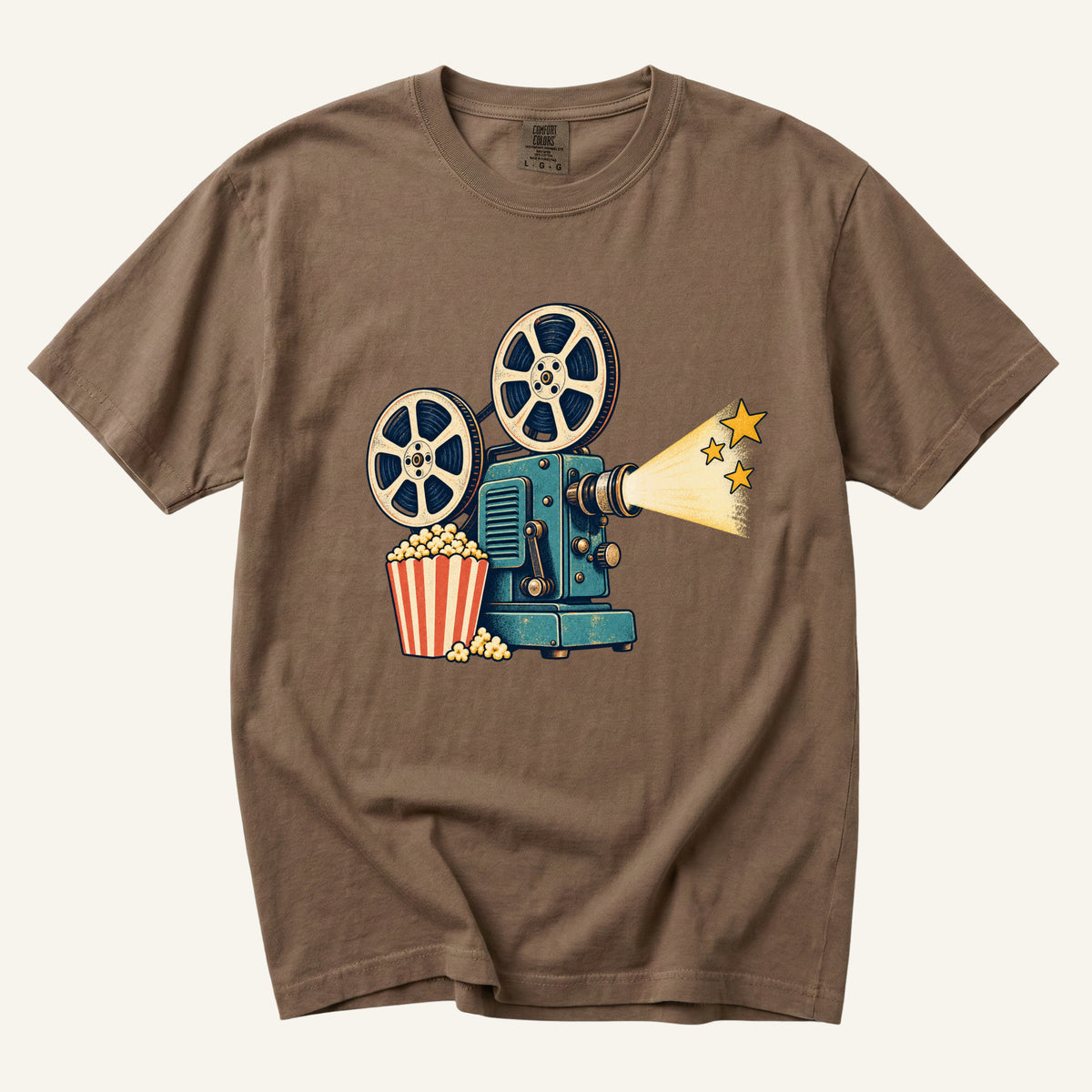 Meet Me at the Movies T-Shirt in Espresso — a teal film projector with cream reels, a striped popcorn carton and a golden beam