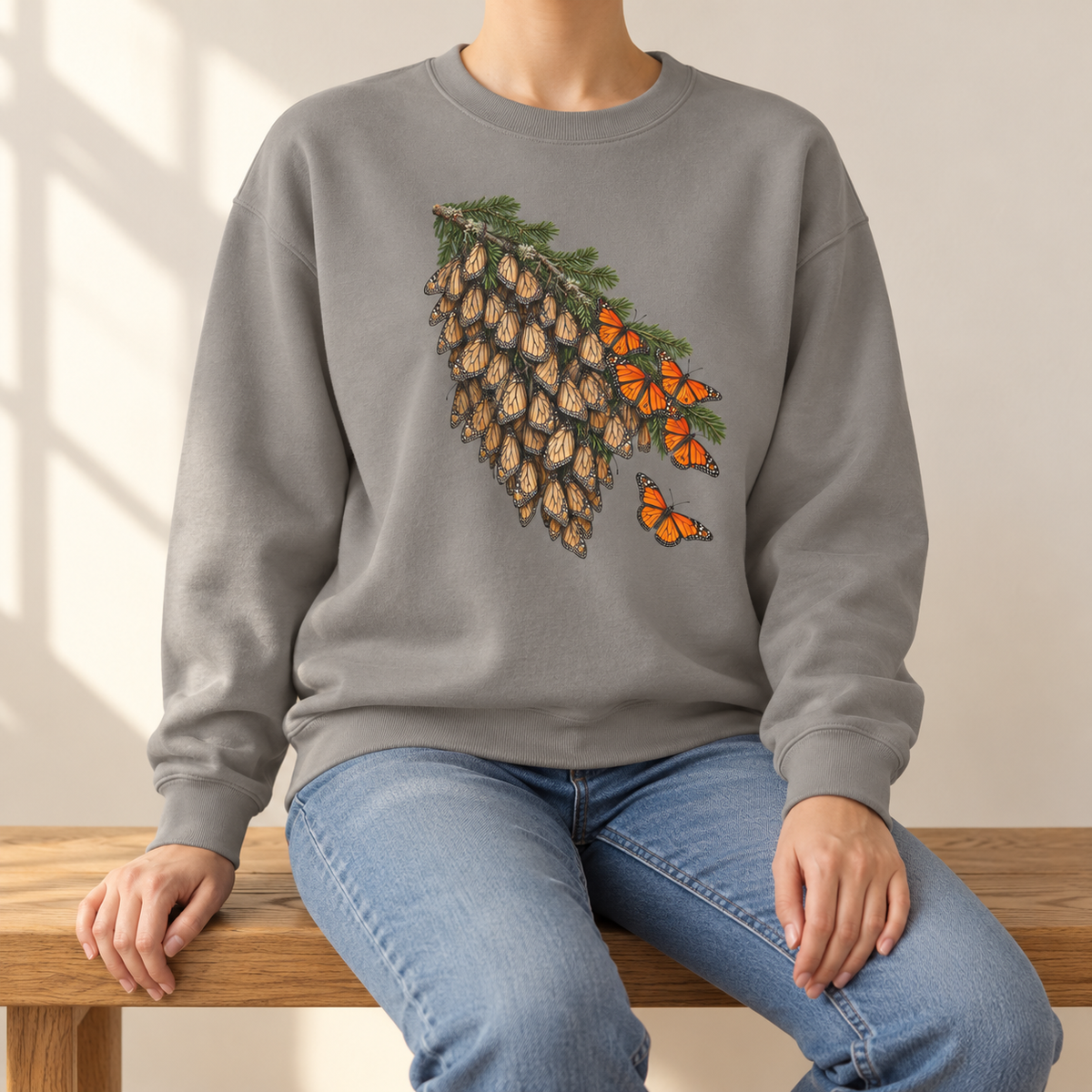 Overwintering Monarchs Sweatshirt in Grey - a watercolor roost of monarch butterflies on a fir bough, wings closed, a few open in the sun, printed on a garment-dyed Comfort Colors 1566 crewneck