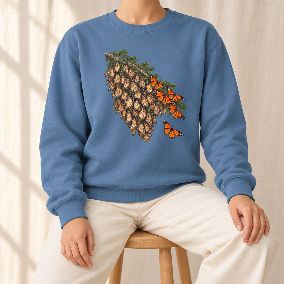 Overwintering Monarchs Sweatshirt in Blue Jean - a watercolor roost of monarch butterflies on a fir bough, wings closed, a few open in the sun, printed on a garment-dyed Comfort Colors 1566 crewneck