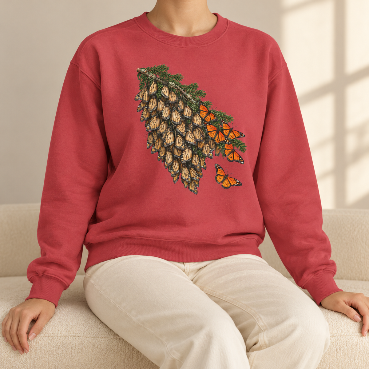 Overwintering Monarchs Sweatshirt in Crimson - a watercolor roost of monarch butterflies on a fir bough, wings closed, a few open in the sun, printed on a garment-dyed Comfort Colors 1566 crewneck