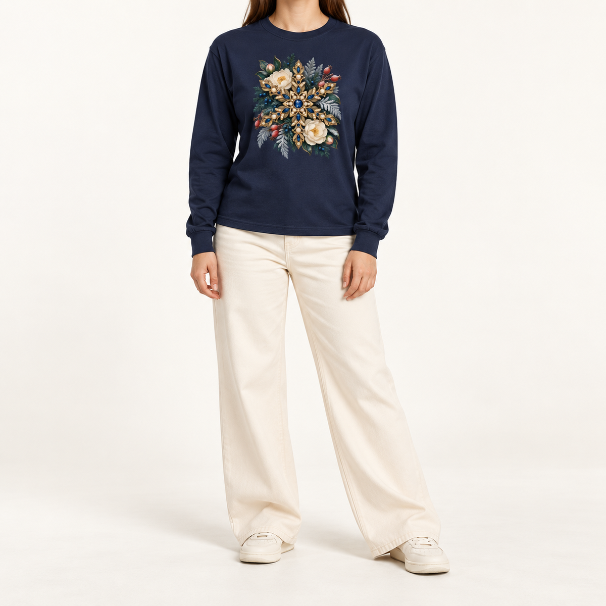 Navy long sleeve tee with a front-centered jeweled snowflake print, straight sleeves and ribbed cuffs — a golden snowflake set with deep blue gemstones and pearls among cream flowers and frosted evergreen