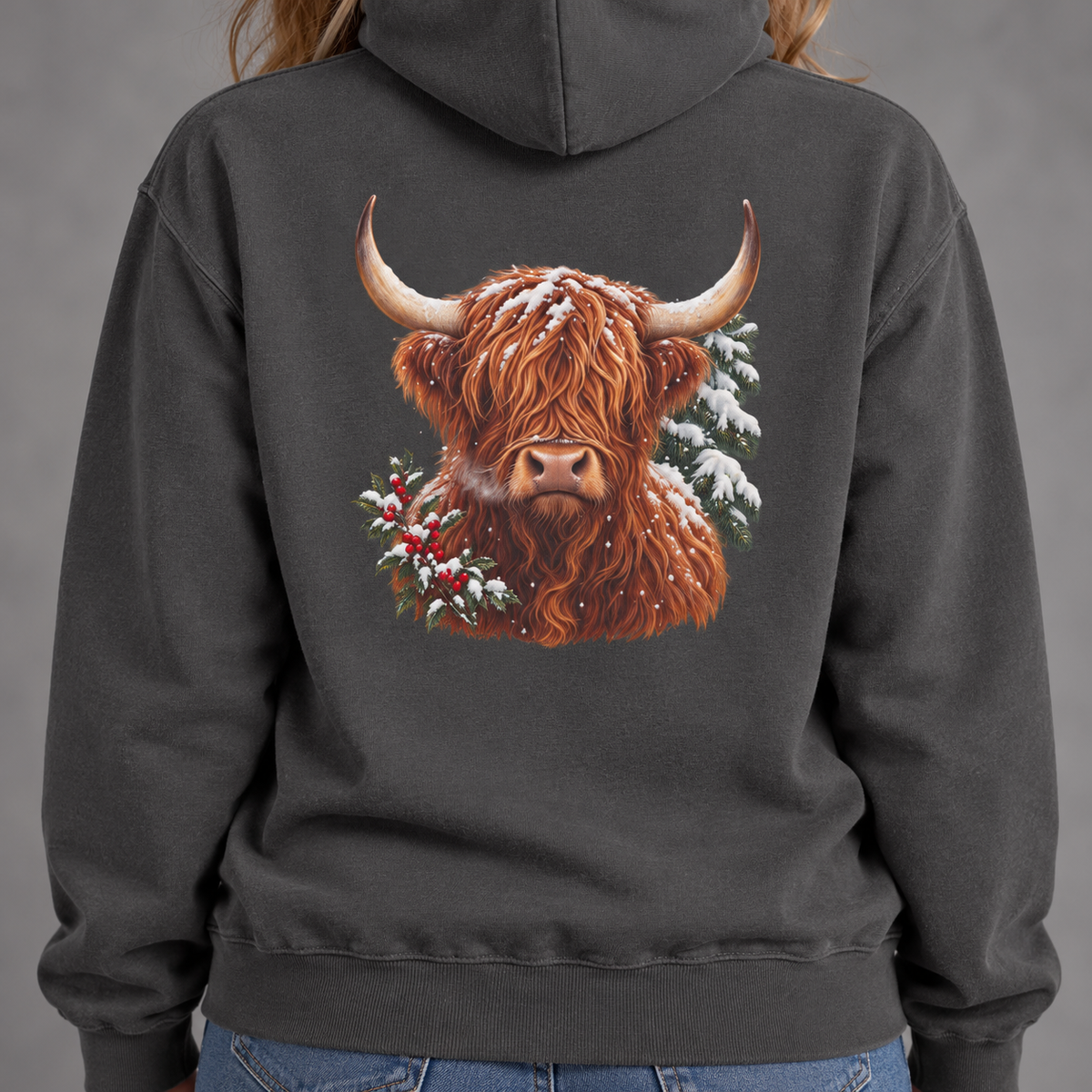 Winter Highland Cow hoodie in Pepper worn, back view with the large highland cow portrait framed by pine and holly