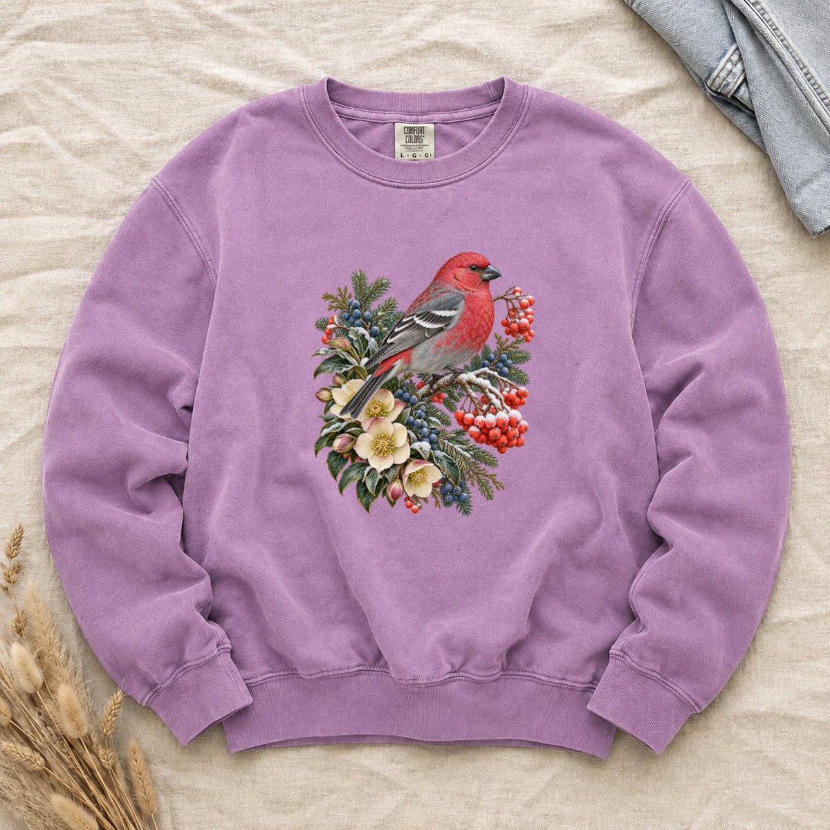 Red Bird & Winter Botanicals Sweatshirt in Orchid — a bright red bird with softly shaded gray wings and a long tail, perched on a branch among evergreen sprigs, red and blue berries and cream flowers