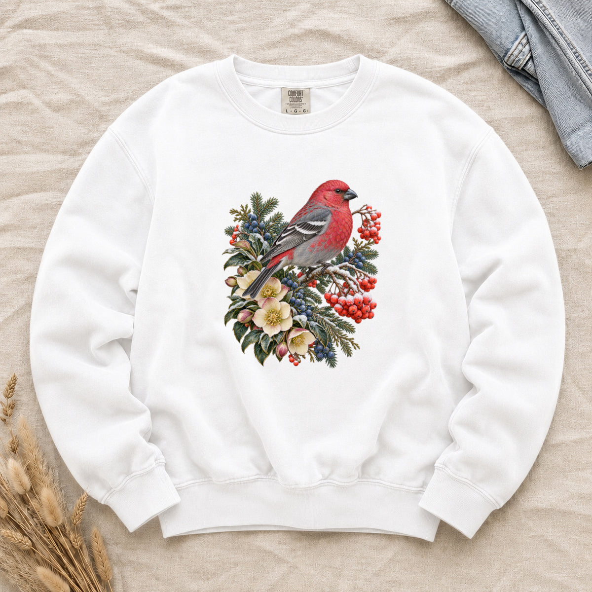 Red Bird & Winter Botanicals Sweatshirt in White — a bright red bird with softly shaded gray wings and a long tail, perched on a branch among evergreen sprigs, red and blue berries and cream flowers