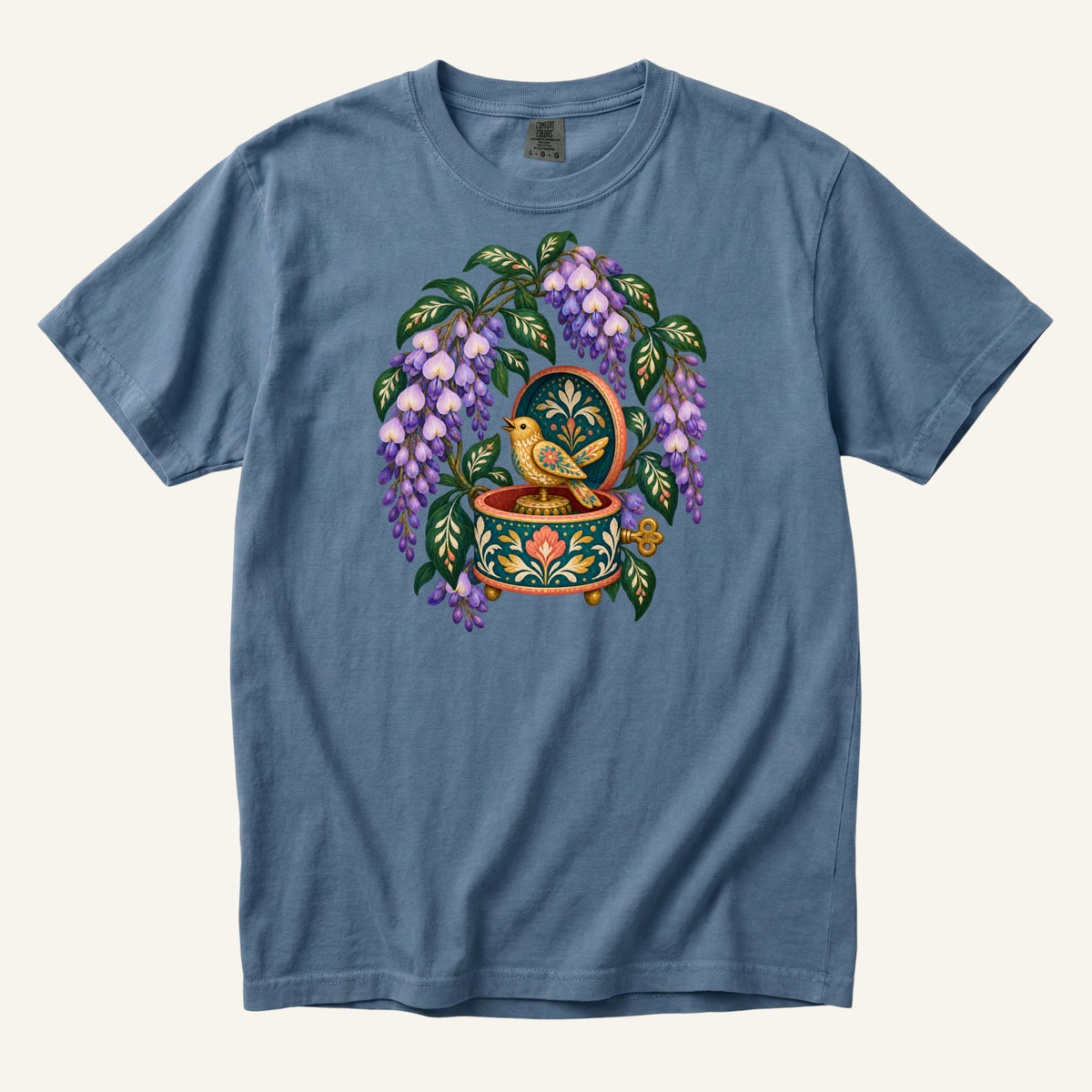 Folk-art music box with purple wisteria and a golden bird illustration on a Blue Jean Comfort Colors t-shirt