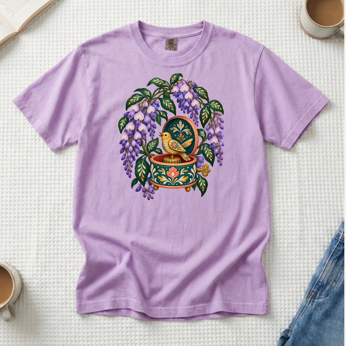Folk-art music box with purple wisteria and a golden bird illustration on an Orchid lilac Comfort Colors t-shirt