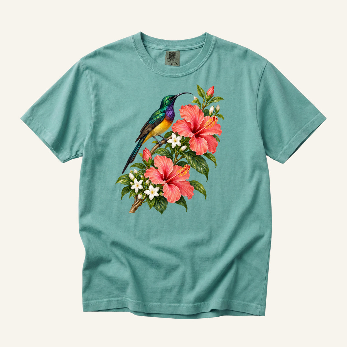 Jewel-colored tropical bird beside coral hibiscus flowers and glossy green leaves, printed on a Chalky Mint green Comfort Colors 1717 unisex t-shirt