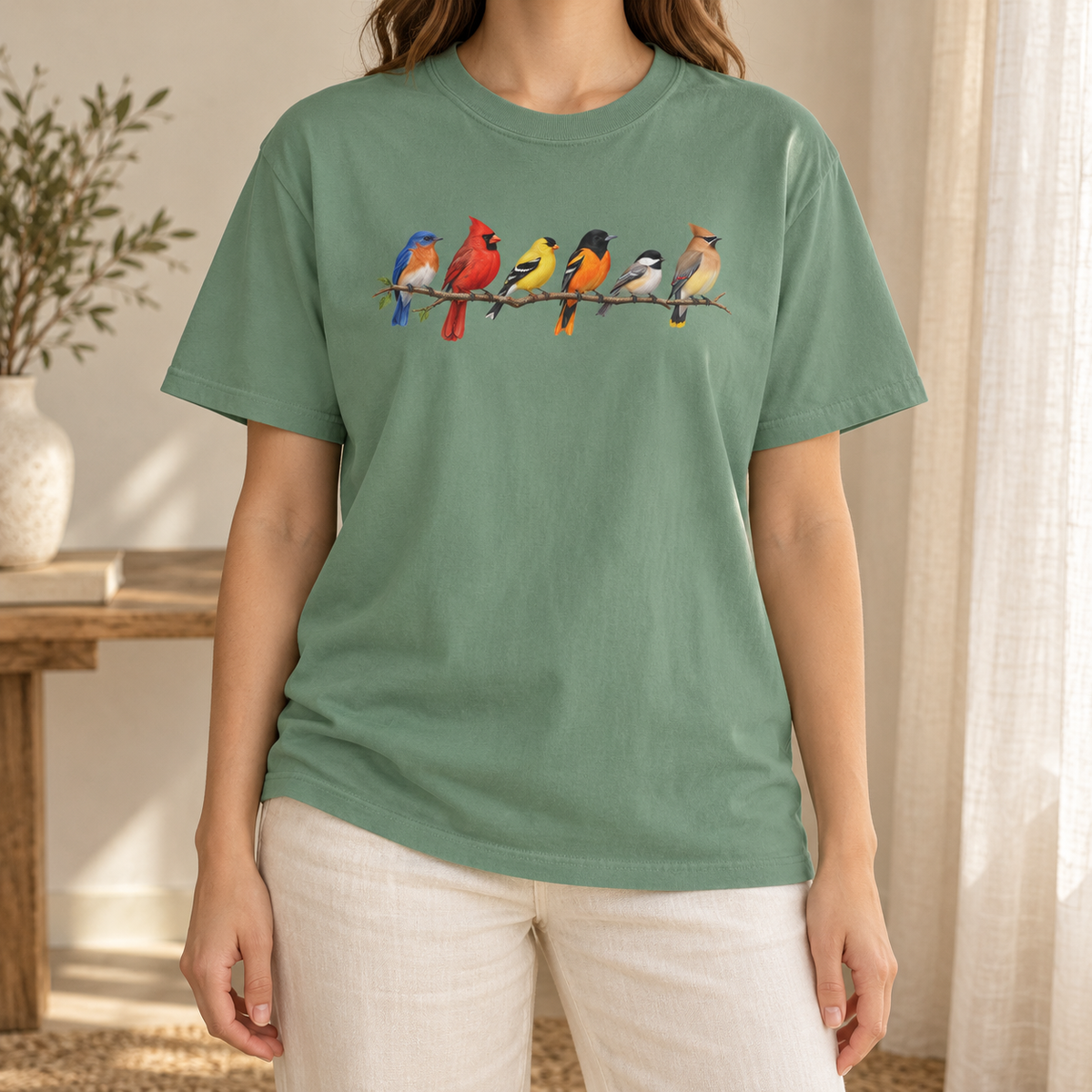 Colorful Birds on Branches t-shirt in Light Green — six painted songbirds on one branch: chickadee, goldfinch, cedar waxwing, northern cardinal, Baltimore oriole and eastern bluebird, on a garment-dyed Comfort Colors tee