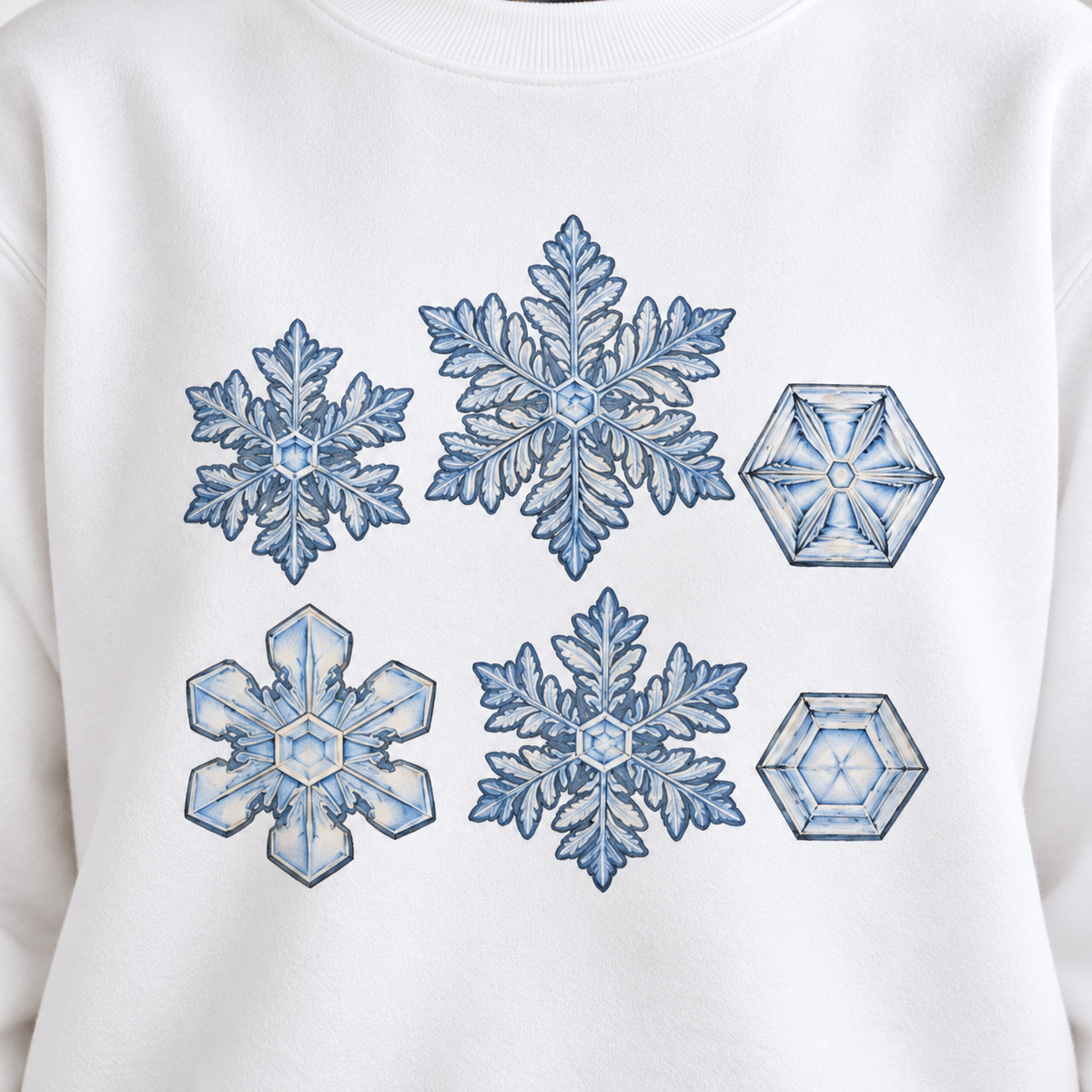 Close-up of the snowflake study print on a white garment-dyed Comfort Colors sweatshirt - six snow crystal forms with ink edges and soft shadows