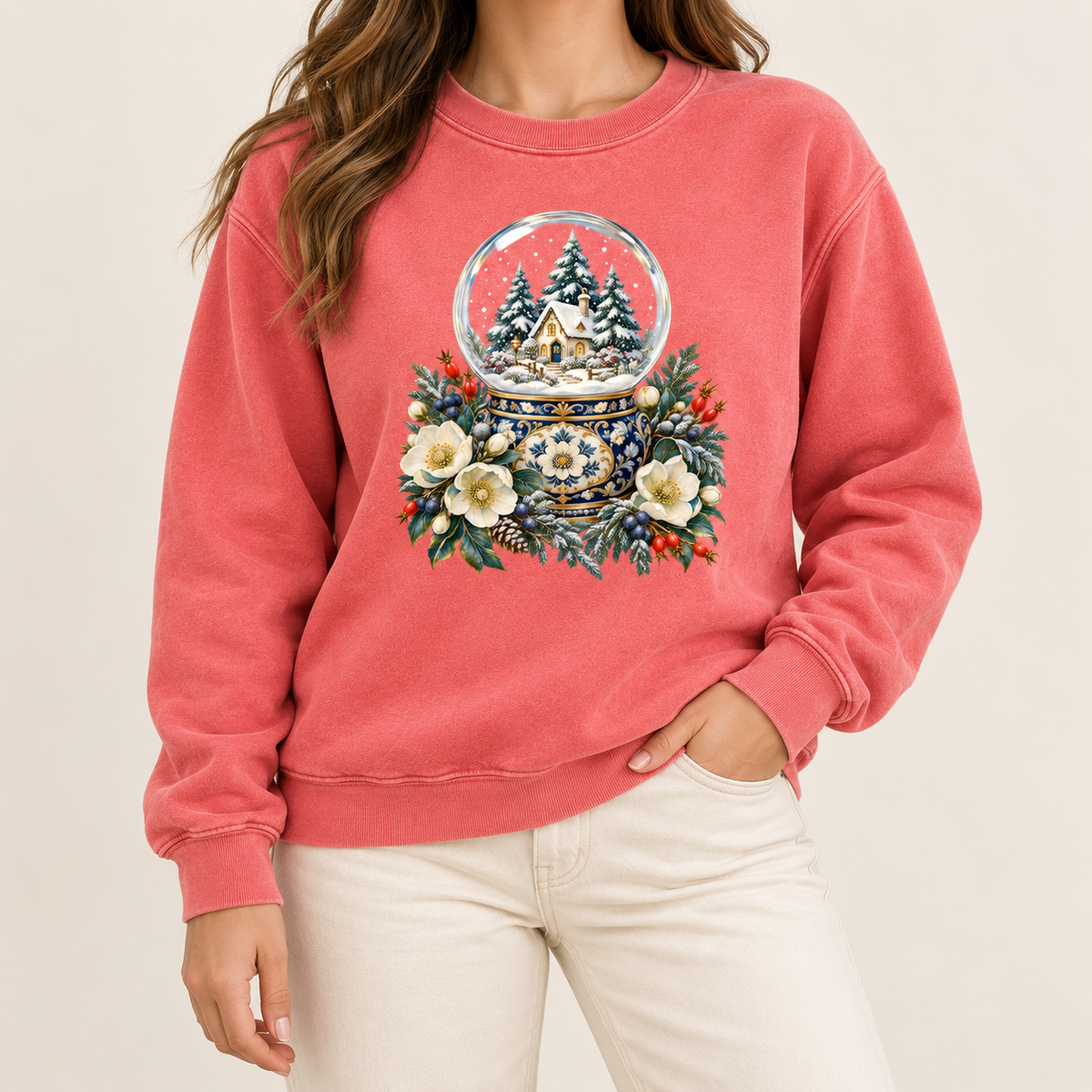 Snow globe and winter florals sweatshirt worn, relaxed unisex fit, adult sizes S to 3XL — a glass snow globe holding a snowy cottage and evergreens on an ornate navy-and-gold base, framed by cream blossoms and red berries
