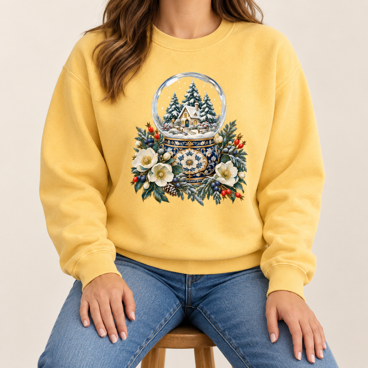 Snow globe and winter florals design printed direct-to-garment on garment-dyed fleece — a glass snow globe holding a snowy cottage and evergreens on an ornate navy-and-gold base, framed by cream blossoms and red berries