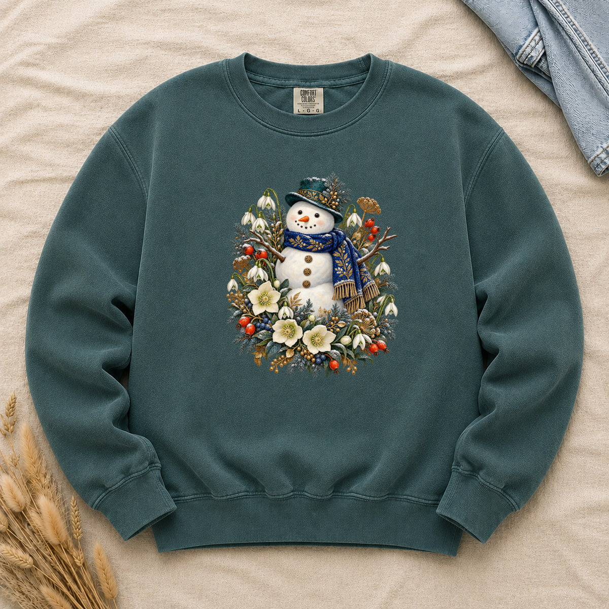 Snowman & Winter Botanicals Sweatshirt in Blue Spruce — a smiling snowman in a decorated dark hat and a deep blue scarf with golden pattern, among evergreen branches, red berries and large cream flowers