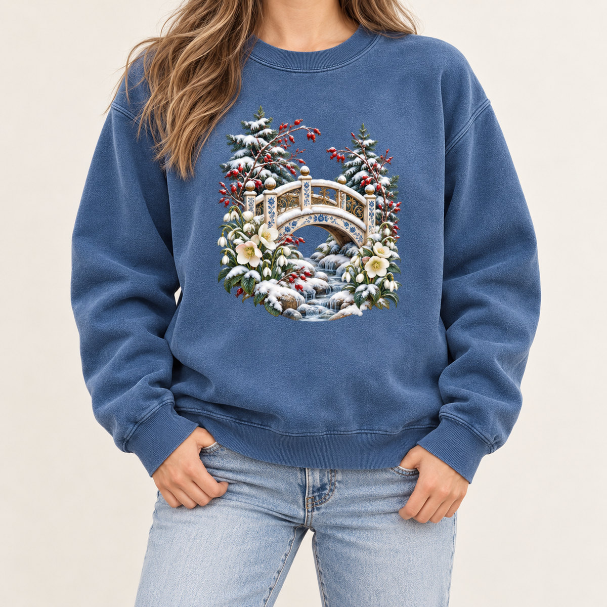 Winter bridge and botanicals design printed direct-to-garment on garment-dyed fleece — an ornate ivory footbridge arching over a snowy rocky stream, framed by evergreen, red berries and cream flowers