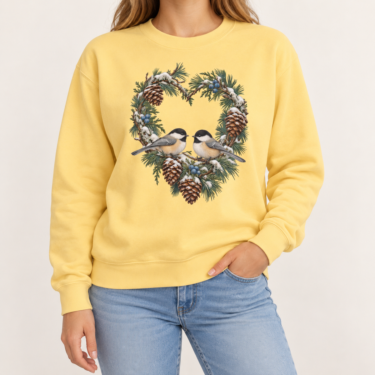 Chickadee heart wreath sweatshirt – a pair of chickadees on a snowy pine heart wreath with pinecones, printed large on the chest of a Comfort Colors crewneck