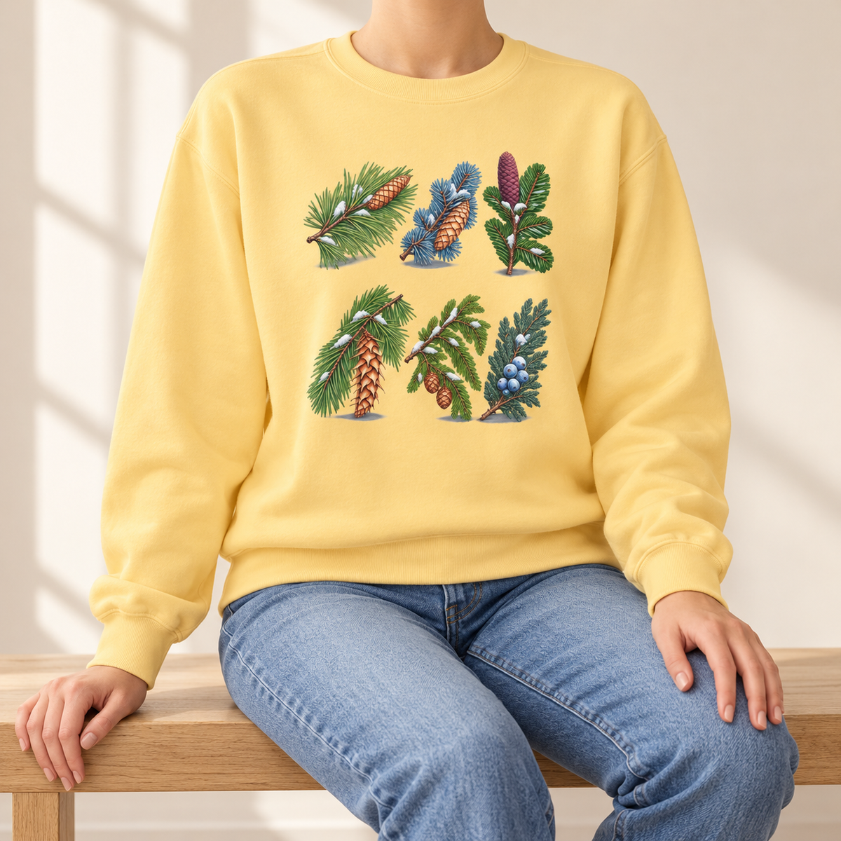 Evergreen Study Sweatshirt in Butter - six watercolor conifer sprigs with cones and snow laid out like a botanical plate, printed on a garment-dyed Comfort Colors 1566 crewneck