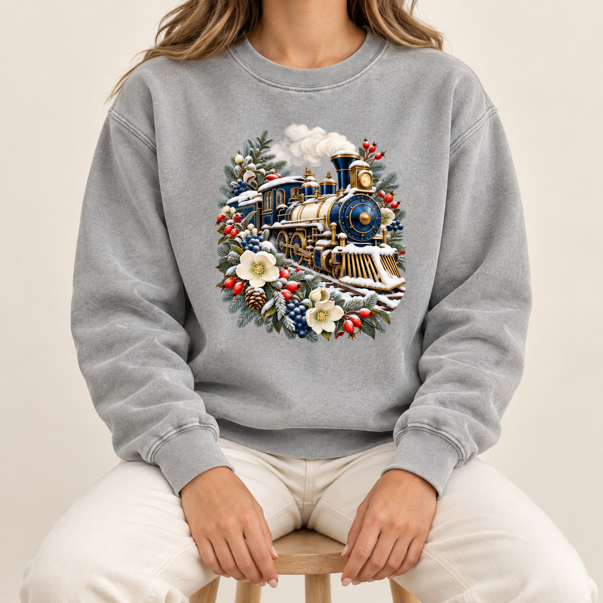 Vintage steam train and winter botanicals print on a 9.5 oz garment-dyed cotton-blend crewneck — a deep blue and gold steam locomotive ringed by snow-dusted evergreen, red berries, pinecones and cream flowers
