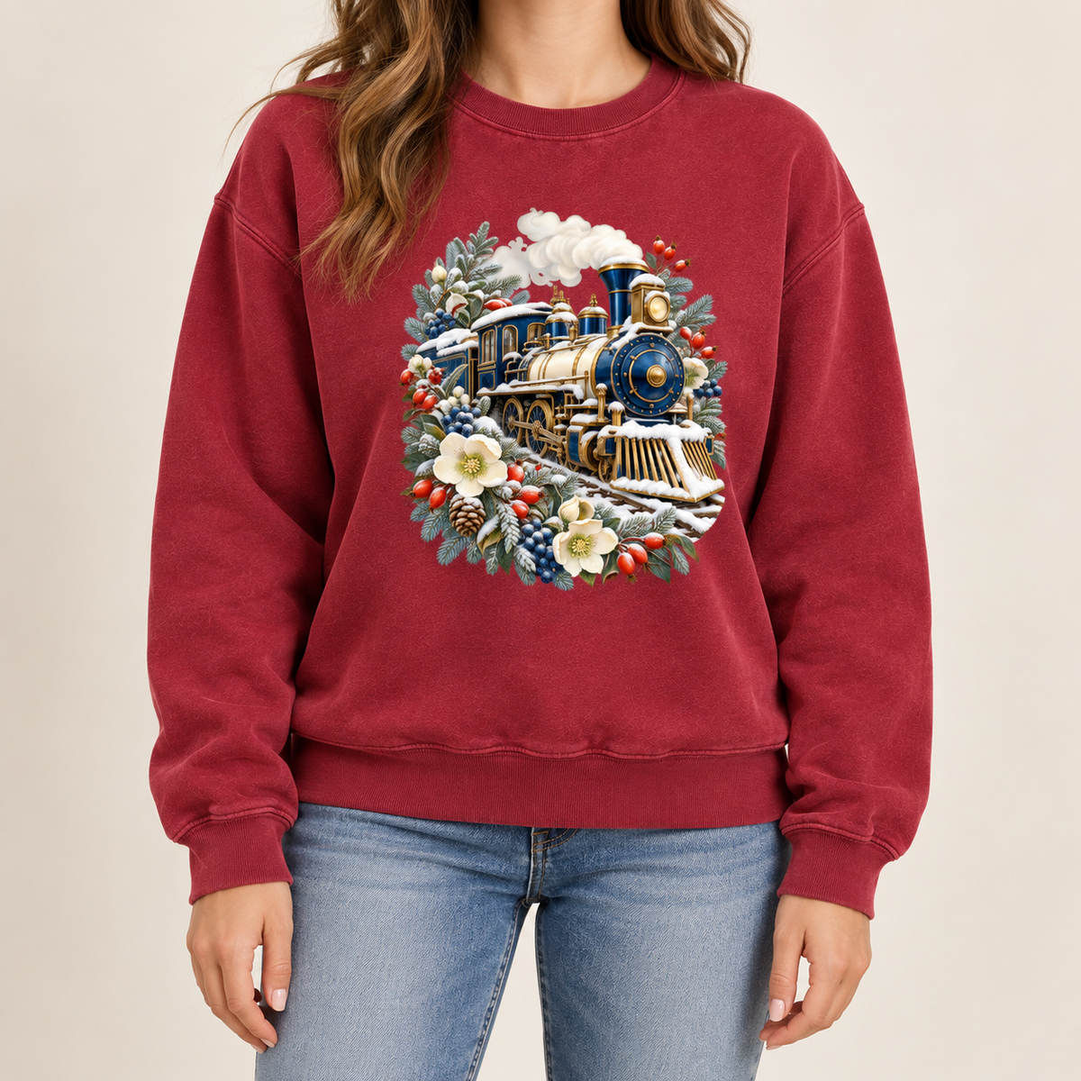 Classic railway illustration on a side-seamed Comfort Colors 1566 crewneck — a deep blue and gold steam locomotive ringed by snow-dusted evergreen, red berries, pinecones and cream flowers