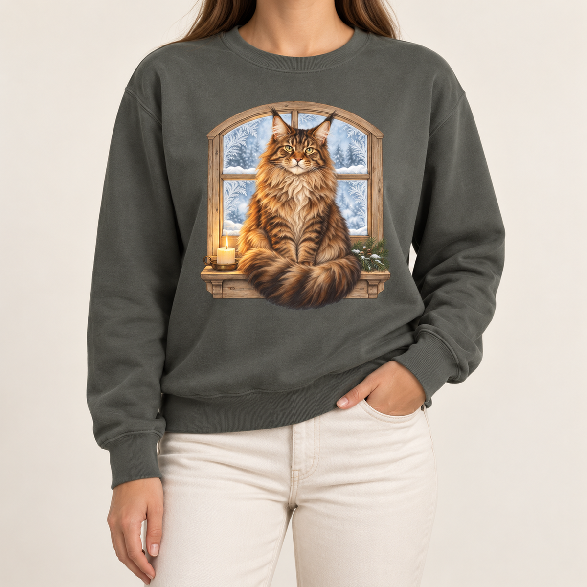 Maine Coon at the window sweatshirt – a tabby Maine Coon on a frosted windowsill with a candle and pine, snowy forest through an arched window, printed large on the chest of a Comfort Colors crewneck