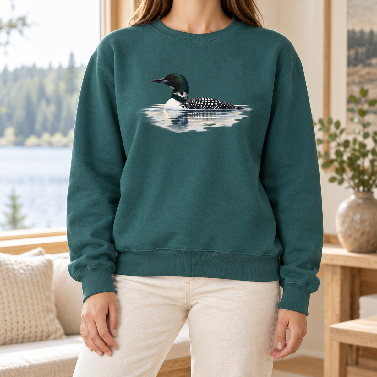 Common Loon Sweatshirt in Blue Spruce - watercolor loon with mist and reflection on a deep evergreen Comfort Colors crewneck, worn in soft window light