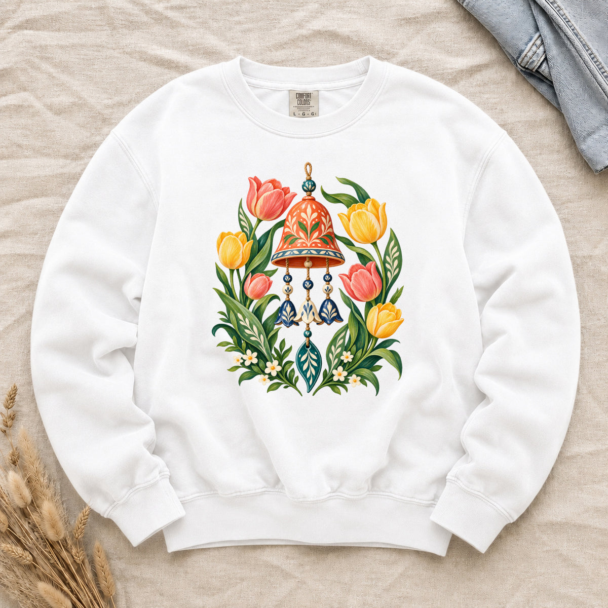 Garden Wind Chime & Tulip Sweatshirt in White — an orange-red garden bell hanging among coral and golden tulips with blue pendants and cream blossoms