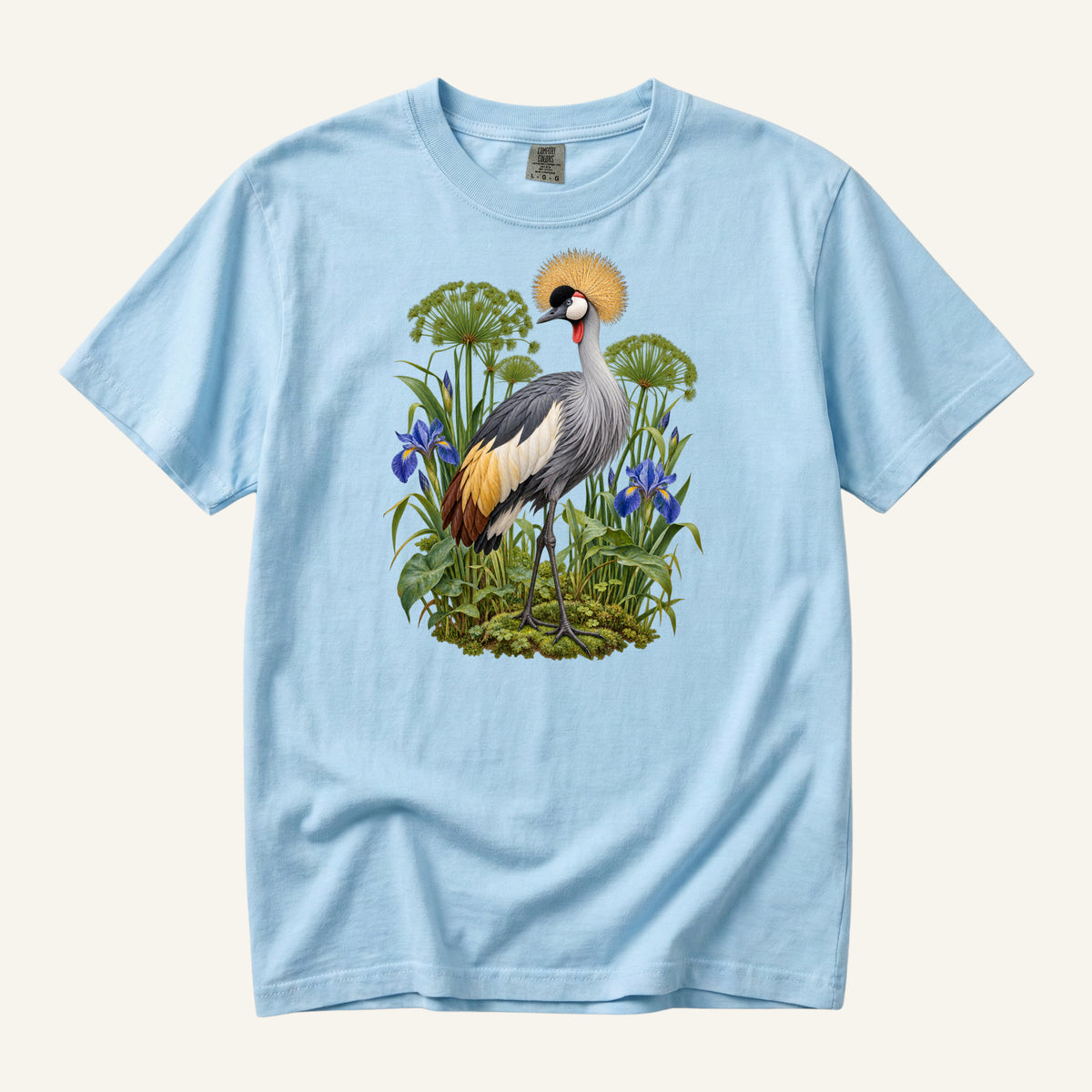 Crowned crane with a golden crest among blue irises and green stems, printed on a Chambray blue Comfort Colors 1717 unisex t-shirt