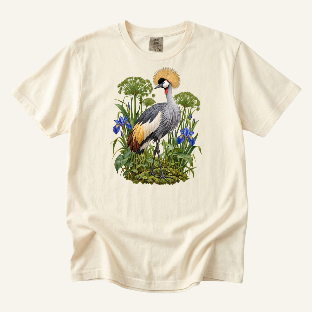 Crowned crane with a golden crest among blue irises and green stems, printed on an Ivory Comfort Colors 1717 unisex t-shirt