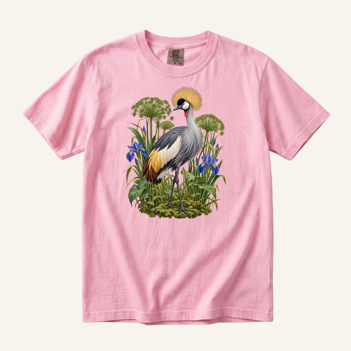 Crowned crane with a golden crest among blue irises and green stems, printed on a Blossom pink Comfort Colors 1717 unisex t-shirt