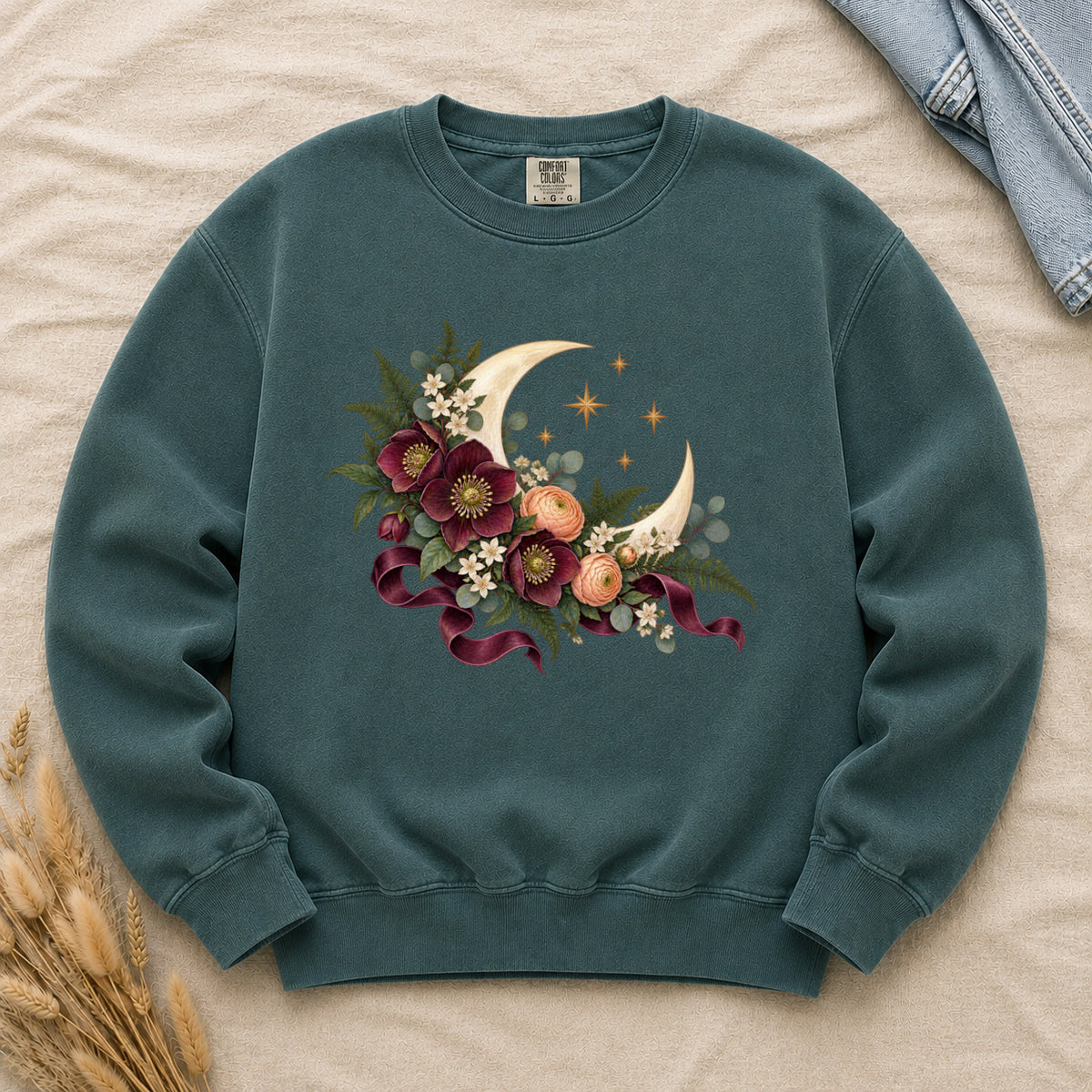 The Garden After Dark sweatshirt in Blue Spruce, a deep blue-green, with a floral crescent moon and burgundy ribbon