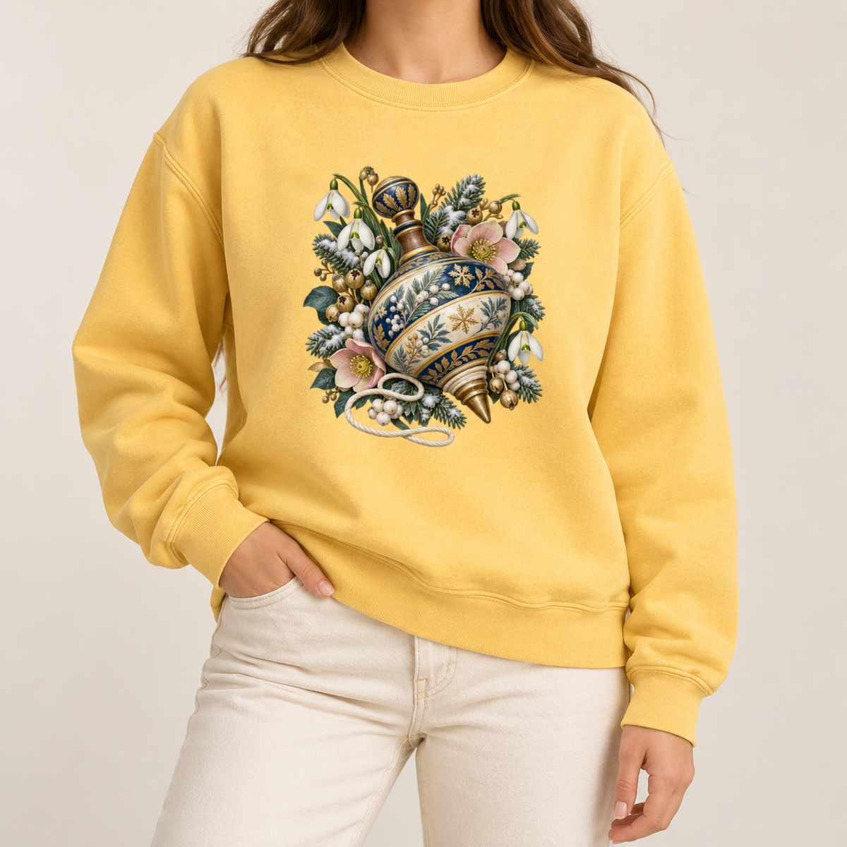 Vintage spinning top and winter florals design on a heavyweight garment-dyed Comfort Colors 1566 crewneck — a deep blue, cream and gold spinning top among evergreen sprigs, white snowdrops, pink flowers and pale berries