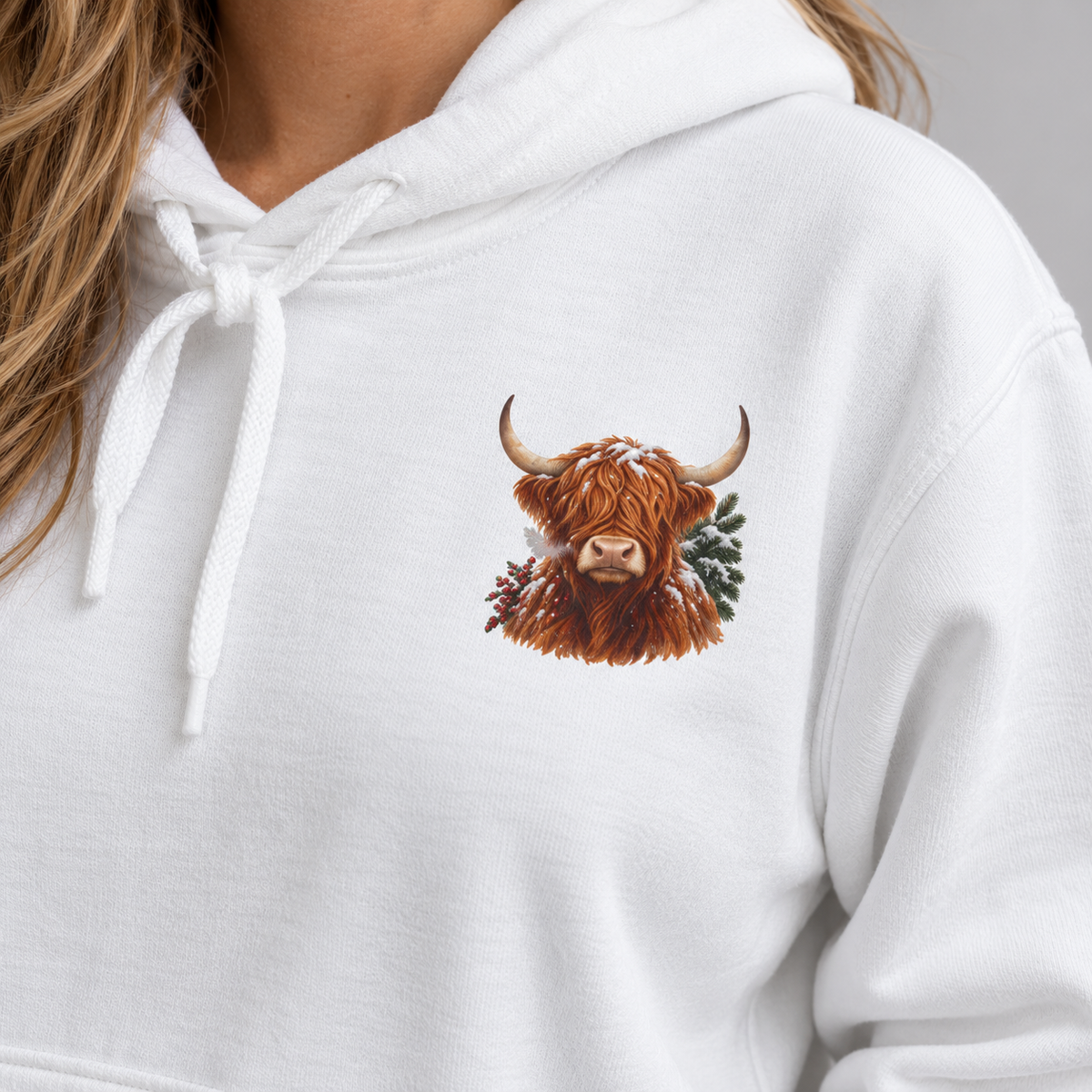 Winter Highland Cow hoodie in White worn, front view with the small highland cow crest on the left chest
