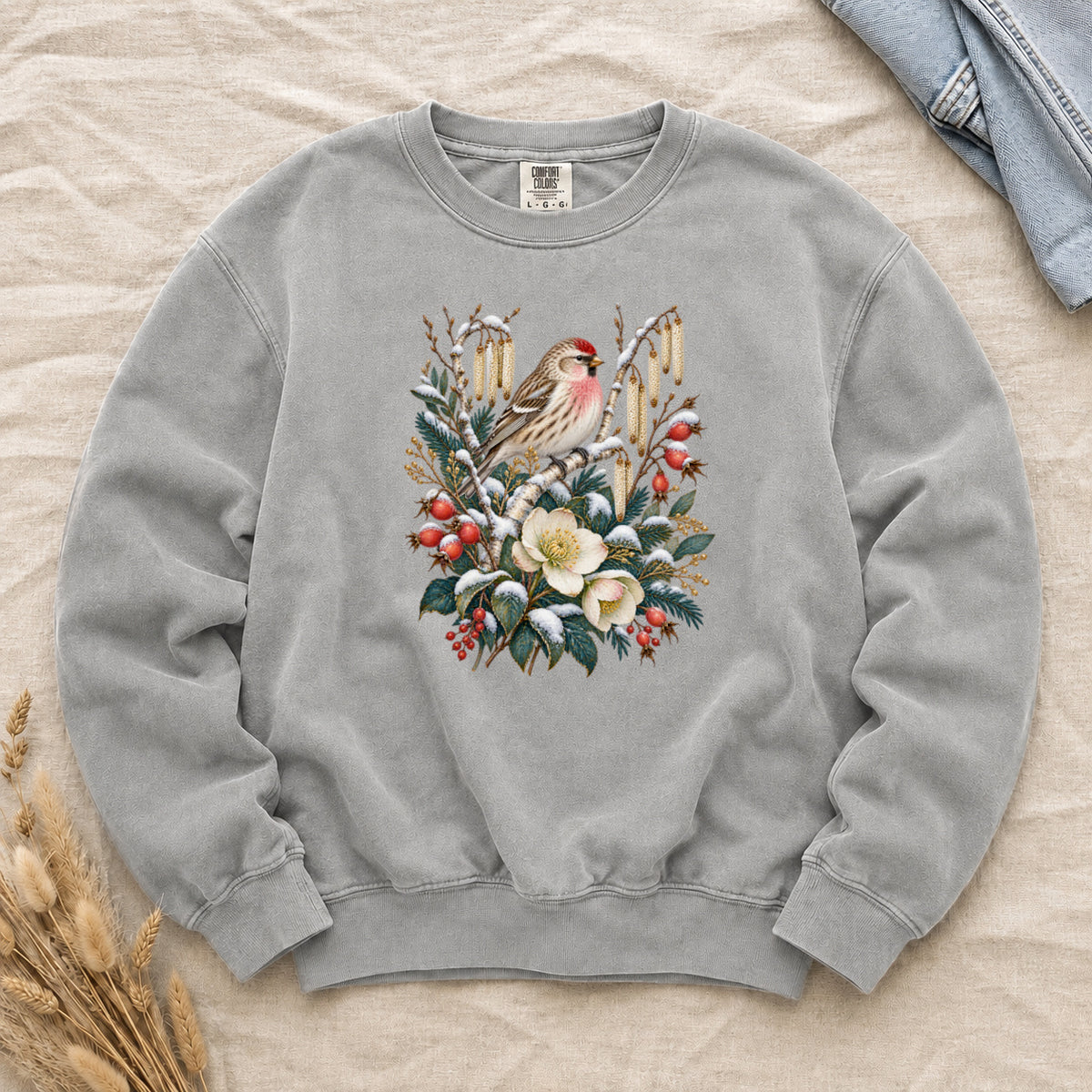 Winter Finch & Botanical Sweatshirt in Grey — a small brown finch with rosy red markings perched among branches hung with golden catkins, above snow-dusted evergreen, red berries and cream flowers