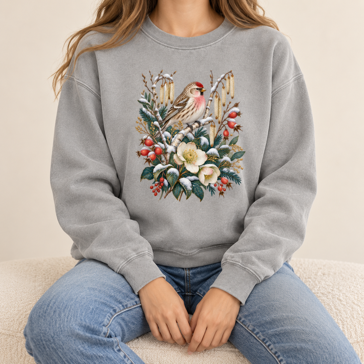 Winter finch and botanical print on a 9.5 oz garment-dyed cotton-blend crewneck — a small brown finch with rosy red markings above snow-dusted evergreen, red berries and cream flowers