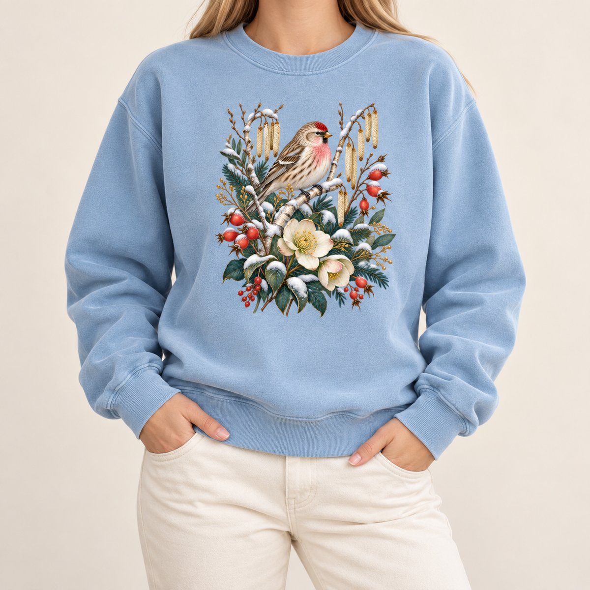 Winter bird crewneck with 1x1 ribbed collar, cuffs and waistband — a small brown finch with rosy red markings above snow-dusted evergreen, red berries and cream flowers