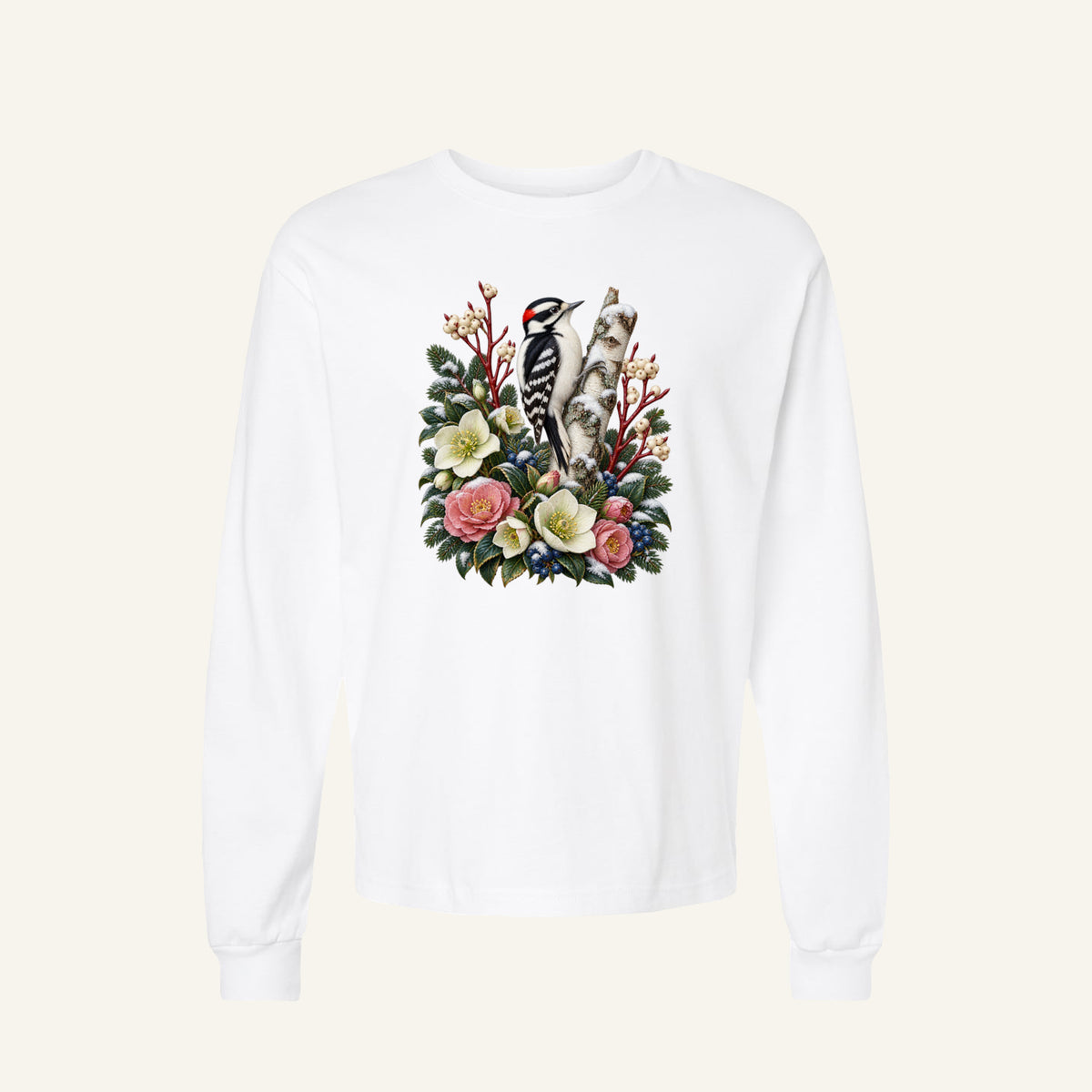 Woodpecker and Winter Florals Long Sleeve Tee in White — a black-and-white woodpecker with a small red patch at the back of its head, clinging to a pale birch trunk among evergreens, cream and pink flowers and winter berries
