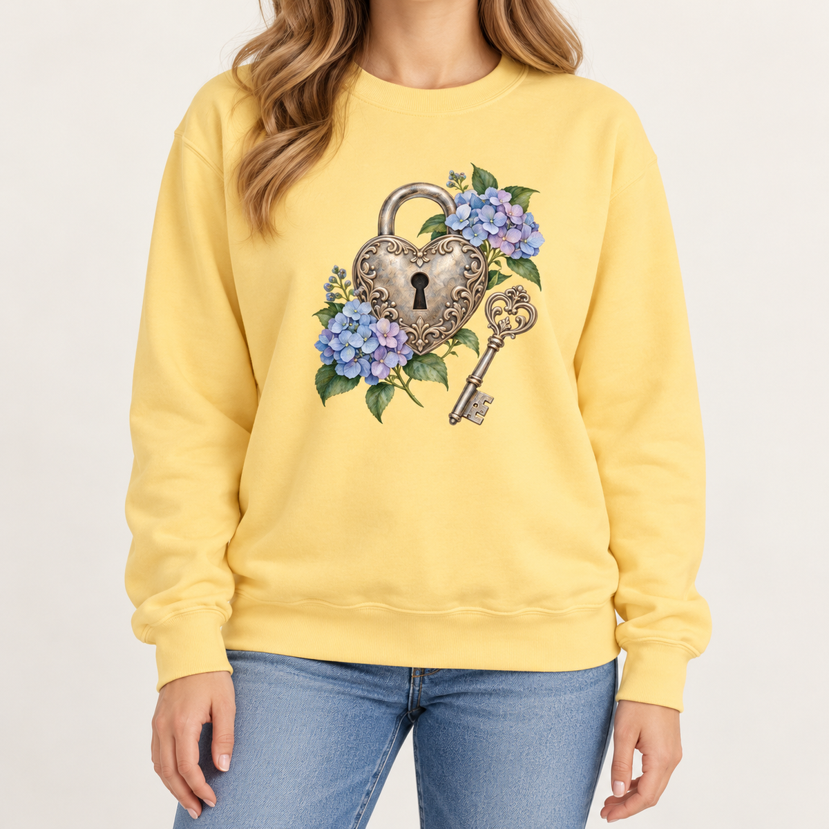 Detailed watercolor of a silver filigree heart padlock and skeleton key among blue and purple hydrangeas, no text, printed large and centered on the front of a Butter soft yellow 9.5 oz garment-dyed Comfort Colors 1566 sweatshirt, worn by a model