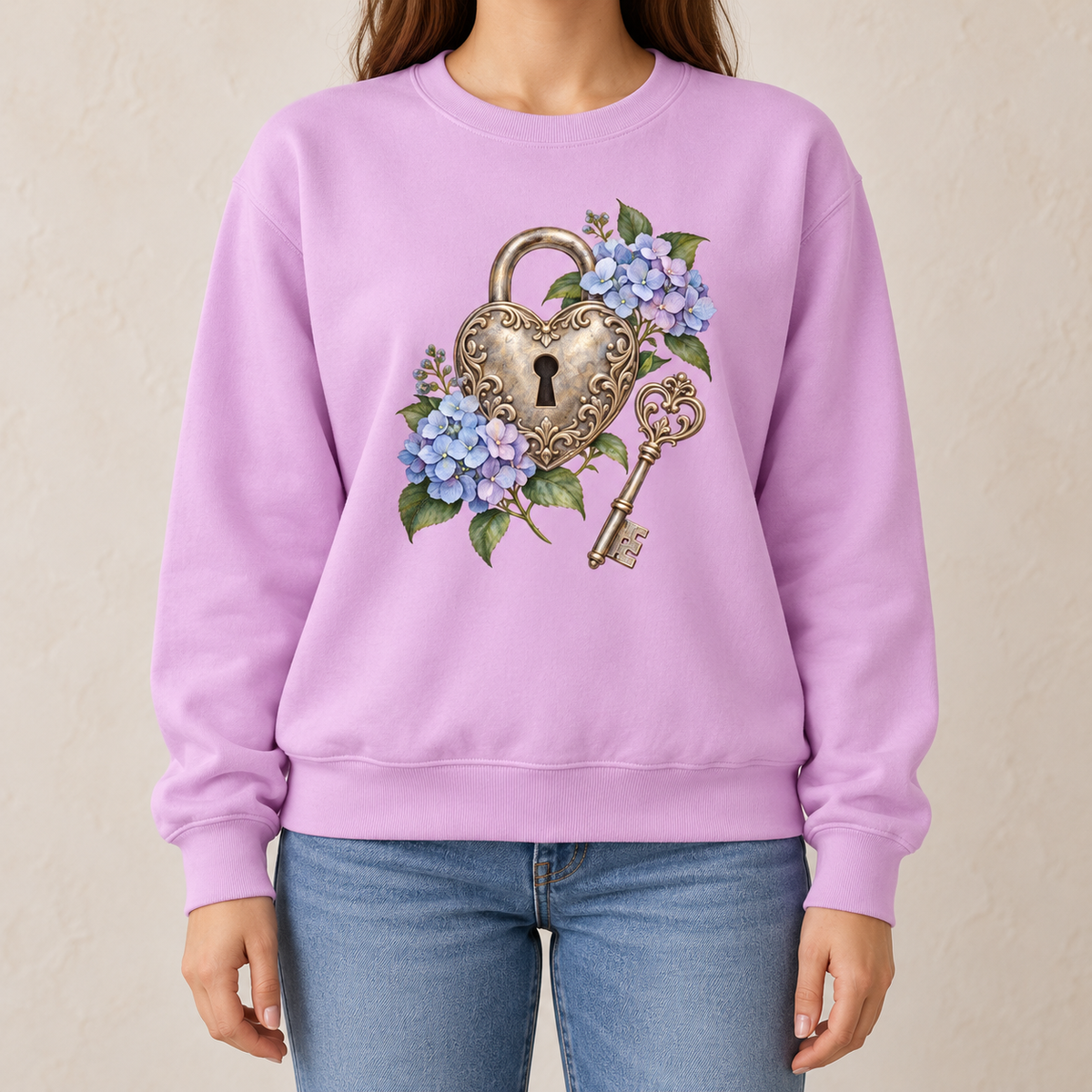 Detailed watercolor of a silver filigree heart padlock and skeleton key among blue and purple hydrangeas, printed large and centered on the front of an Orchid soft lilac 9.5 oz garment-dyed Comfort Colors 1566 sweatshirt, worn by a model