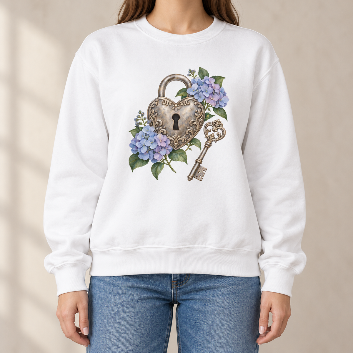 Detailed watercolor of a silver filigree heart padlock and skeleton key among blue and purple hydrangeas, printed large and centered on the front of a White 9.5 oz garment-dyed Comfort Colors 1566 sweatshirt, worn by a model