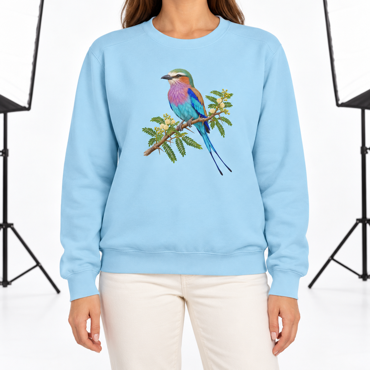 Woman wearing the Lilac-Breasted Roller on Acacia sweatshirt in Chambray, a lilac, turquoise and green roller perched on a flowering acacia branch, large centered chest print