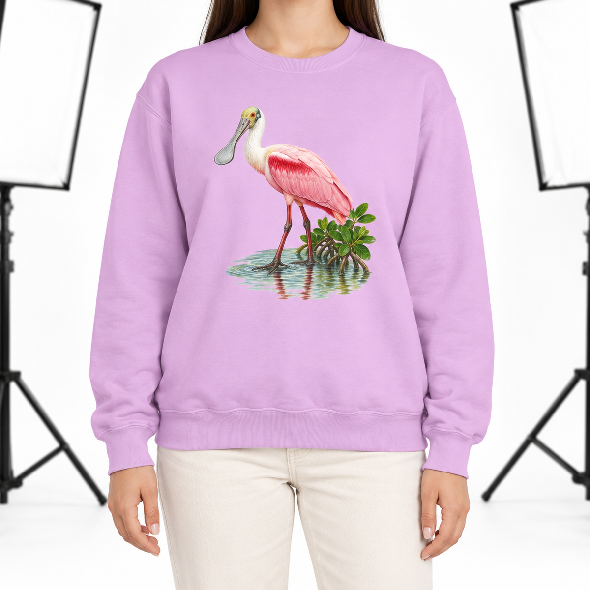 Woman wearing an Orchid Comfort Colors 1566 crewneck sweatshirt with a roseate spoonbill wading in mangrove water printed on the chest, no text