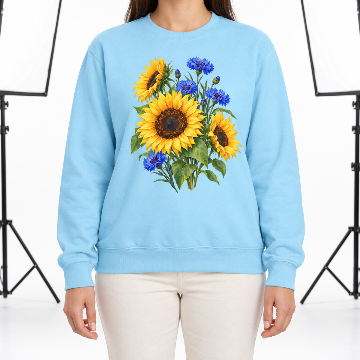 Woman wearing the Golden Sunflowers & Cobalt Cornflowers sweatshirt in Chambray, a bouquet of sunflowers and blue cornflowers as a large centered chest print