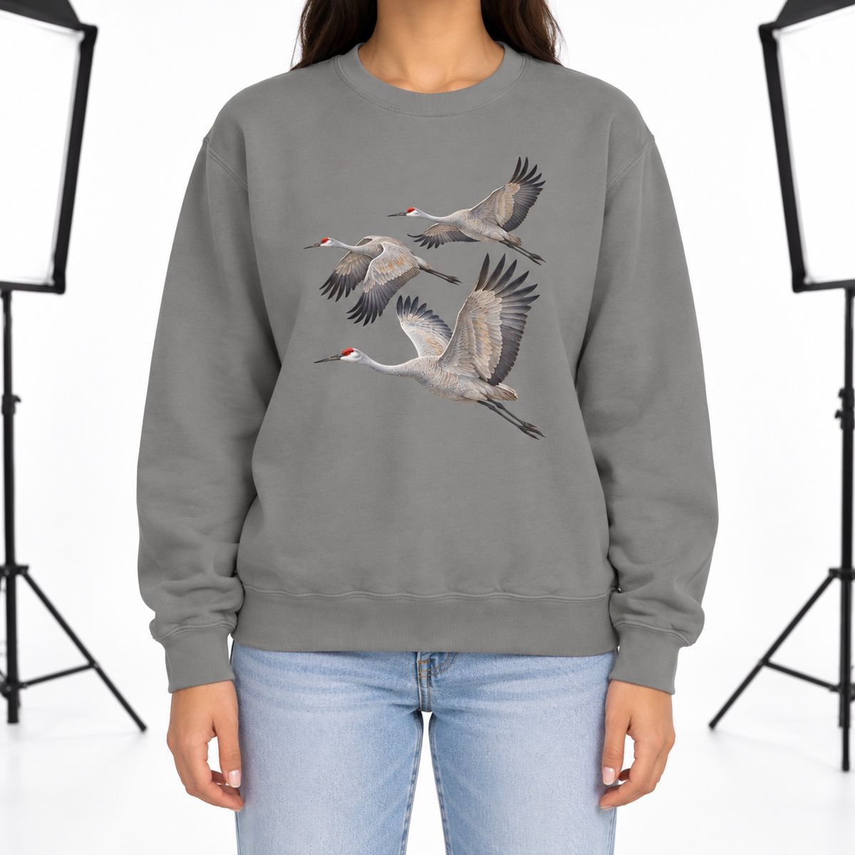 Woman wearing a Grey Comfort Colors 1566 crewneck sweatshirt with three sandhill cranes in flight printed on the chest, no text